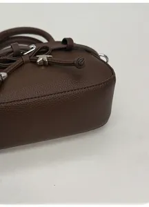 Close-up of brown lychee leather handbag with wide bottom and silver star charm detail