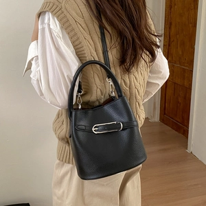 Détail du sac seau en cuir noir grainé avec boucle argentée porté par un modèle