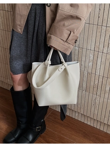 Detail of white lychee leather bucket bag showing texture and metal buckle on a model