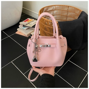 Détail d'un sac seau en cuir grainé rose avec fermoir rotatif et breloque argent