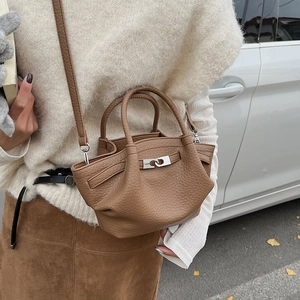 Détail du sac seau en cuir marron avec texture litchi et fermoir tournant en métal argenté