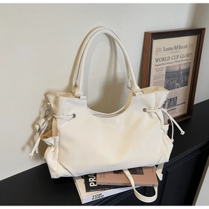 Detail view of cream oversized tote bag with drawstring texture and silver hardware accents