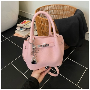 Vue détaillée du sac seau rose en cuir grainé avec fermoir rotatif argenté et breloques