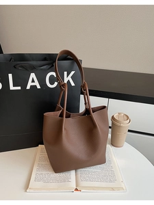 Brown lychee leather tote bag shown on books with a minimalist lifestyle aesthetic