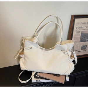 Close-up of cream tote bag featuring adjustable side drawstrings and silver hardware