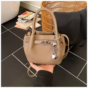 Détail du sac seau en cuir taupe avec breloques argentées et fermoir pivotant argenté