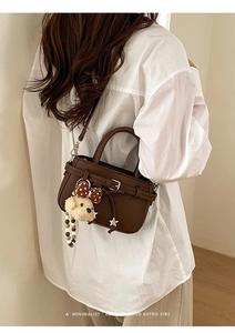 Detail of retro dark brown leather crossbody bag with pleated bow and plush bear charm