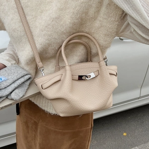 Détail du sac seau en cuir beige à motif litchi avec des ferrures en métal argenté