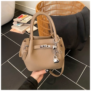 Détail du sac seau en cuir grainé kaki avec charms argentés et fermoir rotatif en métal