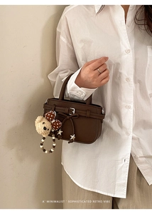 Detail of retro dark brown pebbled leather handbag with bow and plush bear charm