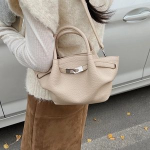 Détail du sac seau en cuir grainé beige avec boucle argentée et doubles poignées rondes
