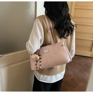 Pink glossy patent leather tote bag detail with plush bear charm and metallic logo tag