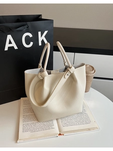 Close-up of cream bucket tote bag with lychee grain texture and metal rivet details