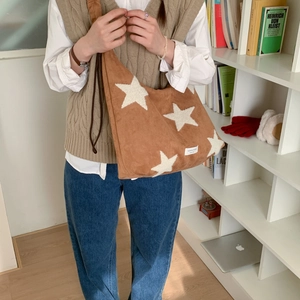 Detail of star-embroidered brown faux suede shoulder bag with wide strap and side label