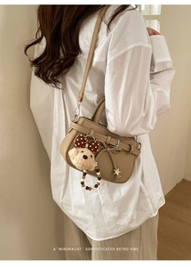 Detail der beigen Handtasche mit Schleife, Sternanhänger und Teddybär-Plüschtier