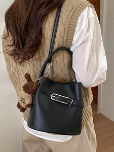 Sac seau en cuir noir avec petit ours, porté par un mannequin dans un intérieur élégant