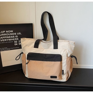 Detailed view of color-block nylon tote bag with front pocket and side drawstring pockets