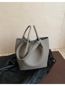 Detail of grey lychee textured leather bucket bag with decorative metal buckle strap