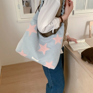 Detail of light blue shoulder bag featuring pink star patch and pleated strap detail