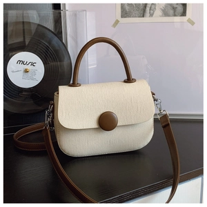 Detalle del bolso bandolera de lona beige y cuero marrón en un ambiente vintage