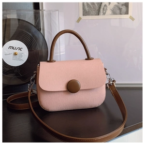 Vista superior del mini bolso bandolera de tela rosa con asa marrón sobre fondo de disco vintage