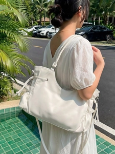 Minimalist creamy white oversized tote bag with drawstring detail shown in outdoor setting