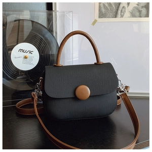 Detalle de bolso vintage de lona con asa de cuero y cierre redondo sobre fondo vinilo