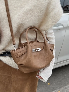 Sac seau chic en cuir caramel avec fermoir argenté porté à l'épaule dans la rue