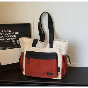 Close-up of color-block tote bag with leather logo patch and functional side pockets