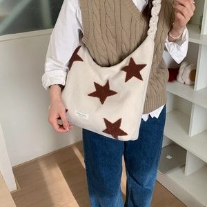 Detail of white star pattern shoulder bag with ruched strap and brand label
