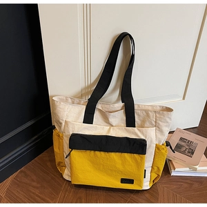 Detailed close-up of a large color-block tote bag with zipper pockets and side drawstrings