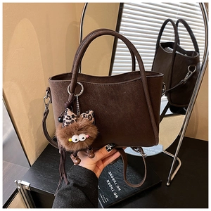 Detailed close-up of dark brown bucket bag with plush charm and leopard bow