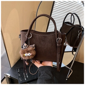 Close-up of brown matte bucket bag featuring wavy edges and a cute plush charm