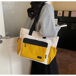 Detail of multi-pocket canvas tote bag with contrast yellow pockets and side drawstring