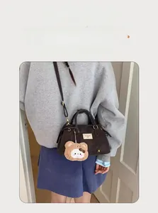 Detail of dark brown vintage crossbody bag with cute plush bear charm and long strap
