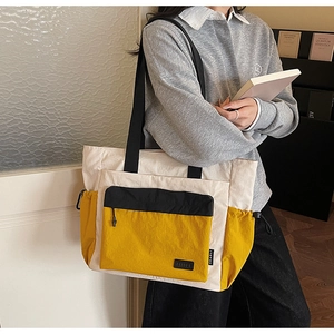 Detail of color-block canvas tote with drawstring side pocket and black zipper compartment
