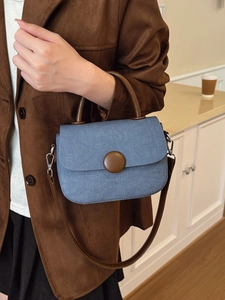 Bolso bandolera de mezclilla azul con asas de cuero marrón usado por una modelo
