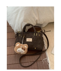 Detail of dark brown leather handbag with vintage metal hardware and plush bear charm