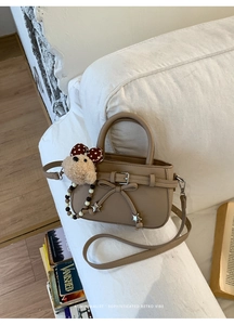 Detail der khakifarbenen Handtasche mit Sternanhängern und süßem Bären-Plüschtier