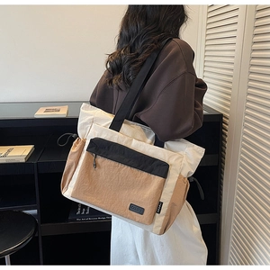 Side view of large color-block canvas tote bag worn by a model in a minimalist room