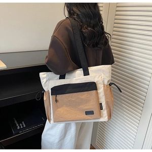 Close-up of color-block tote bag with drawstring side details and outer zipper pocket