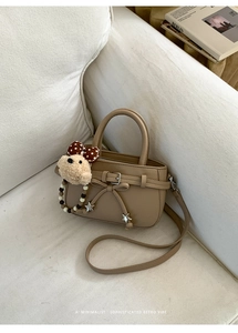 Detail der khakifarbenen Ledertasche mit Schleife, Sternanhänger und Plüschhund