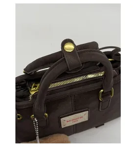 Detail of dark brown matte handbag featuring vintage gold hardware and brand leather patch