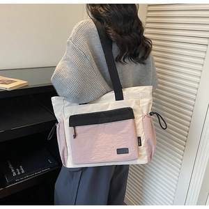 Detail of color-block canvas tote bag featuring side drawstring pocket and utility pouches