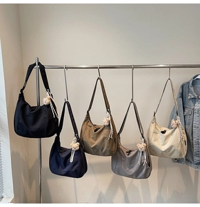 Detail of five hobo shoulder bags in nylon colors with teddy bear charms on metal rack