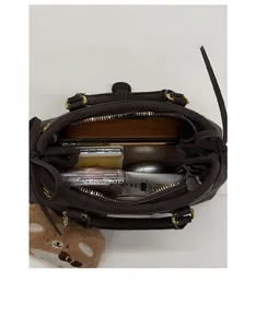 Vertical view of a deep brown tote bag with spacious interior and gold zippers