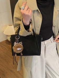 Retro black matte tote bag with fuzzy leopard-print monster charm on a stylish model