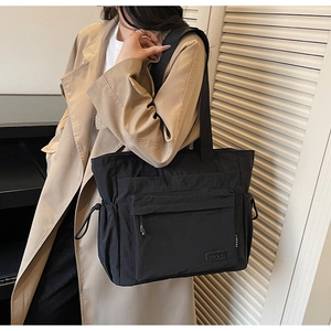 Close-up of black waterproof nylon tote bag with functional drawstring and zipper pocket