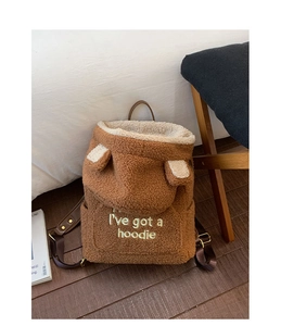 Close-up of brown plush teddy fleece backpack with white hoodie embroidery detail