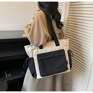 Detail of contrast nylon tote bag featuring front zipper pocket and CK&BLI brand label